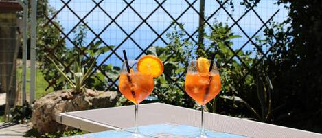 Deux boissons sur une table, avec une vue sur la mer et une clôture en arrière-plan.