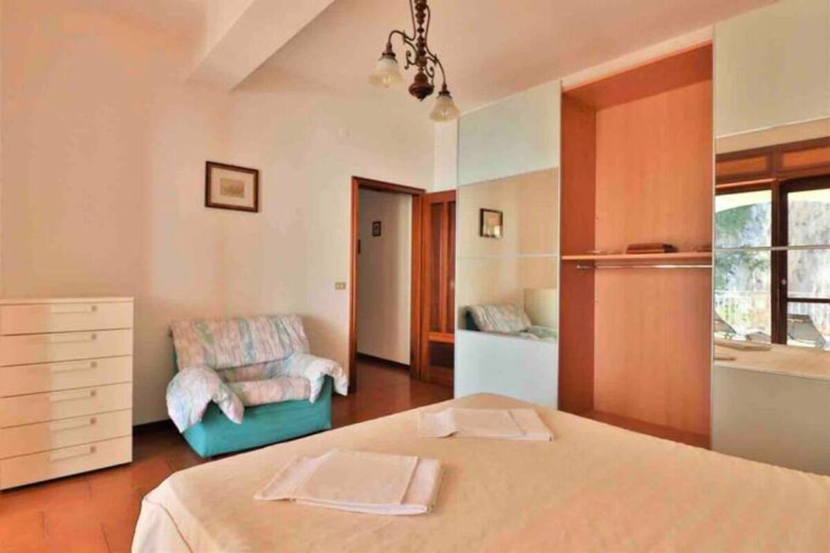 Un dormitorio con cama, cómoda, silla y ventana.