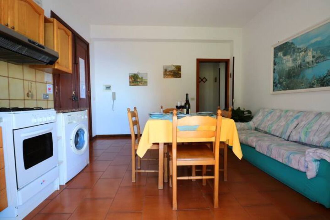 Un espacio habitable compacto con una mesa de comedor, sillas, un sofá, lavadora y estufa.