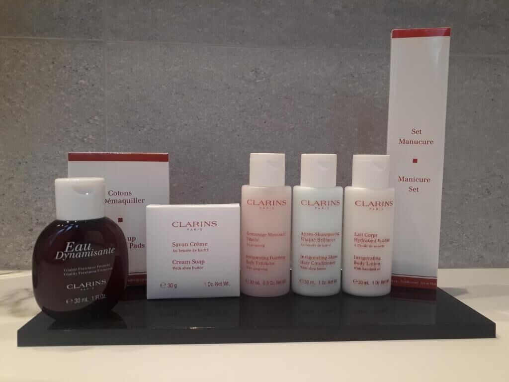 A display of Clarins skincare products on a black stand against a grey wall.