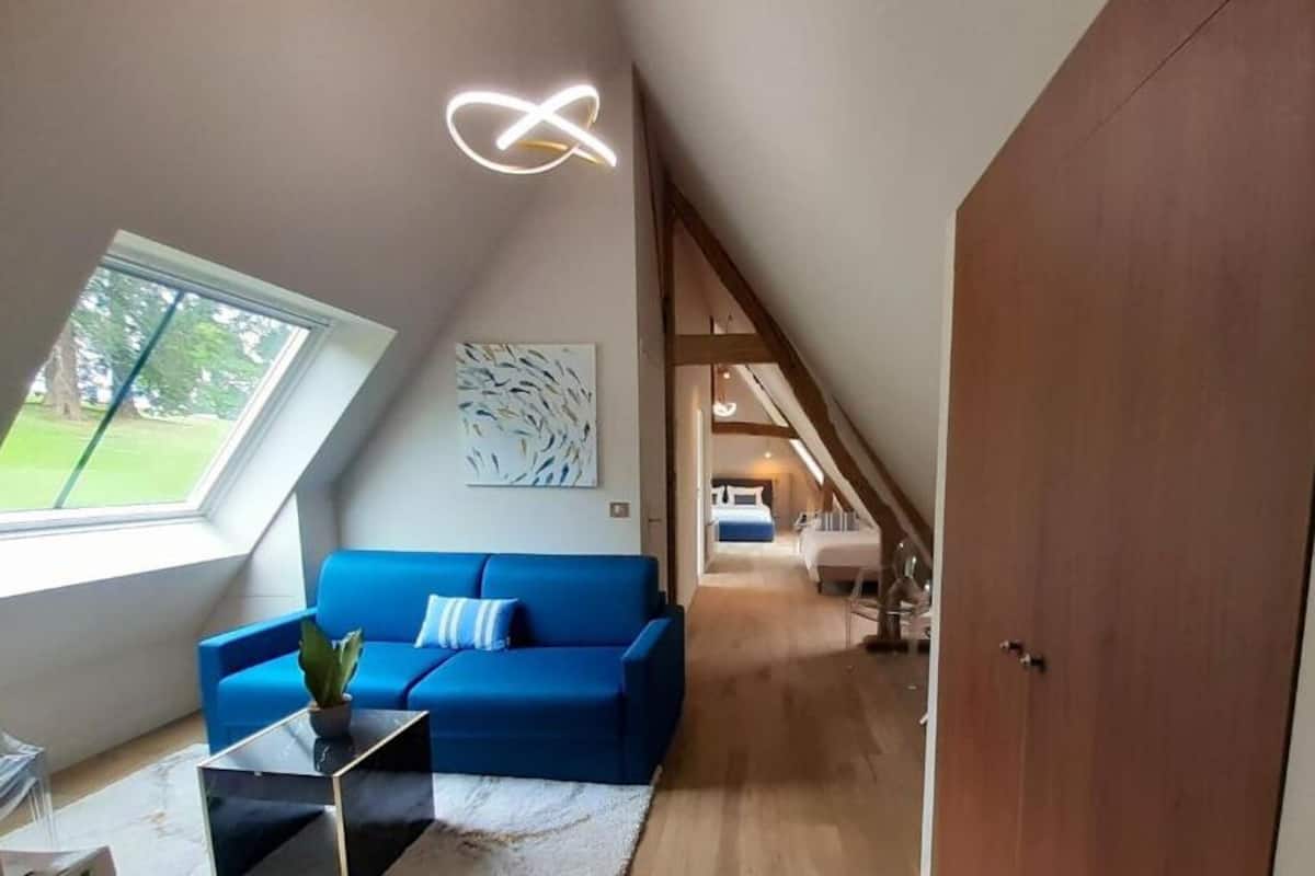 Et moderne loftrum med en blå sofa, et ovenlys, en trædør og en trappe til et højere niveau.
