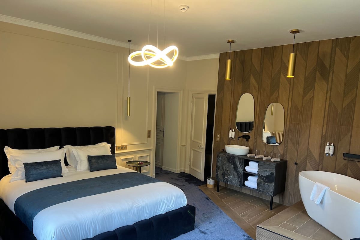 Et moderne hotelværelse med en stor seng, et sminkebord med spejl og et badekar.