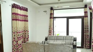 Una sala de estar con un sofá, un tapete estampado y cortinas.