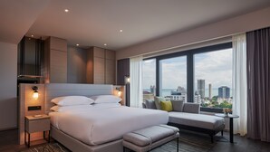 A modern hotel room with a large bed, a seating area, and a city view. - Courtyard by Marriott Penang (George Town)