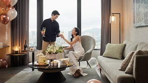 A modern living room with a city view, a round coffee table with a cake and gifts, and a sofa with cushions. - Courtyard by Marriott Penang (George Town)