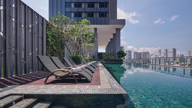 A rooftop infinity pool with clear water, sun loungers, and a view of a city skyline. - Courtyard by Marriott Penang (George Town)