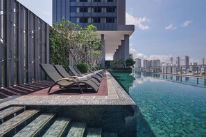 A rooftop infinity pool with clear water, sun loungers, and a view of a city skyline. - Courtyard by Marriott Penang (George Town)