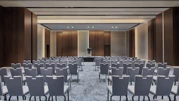 A conference room with rows of chairs, a podium, and a carpeted floor.