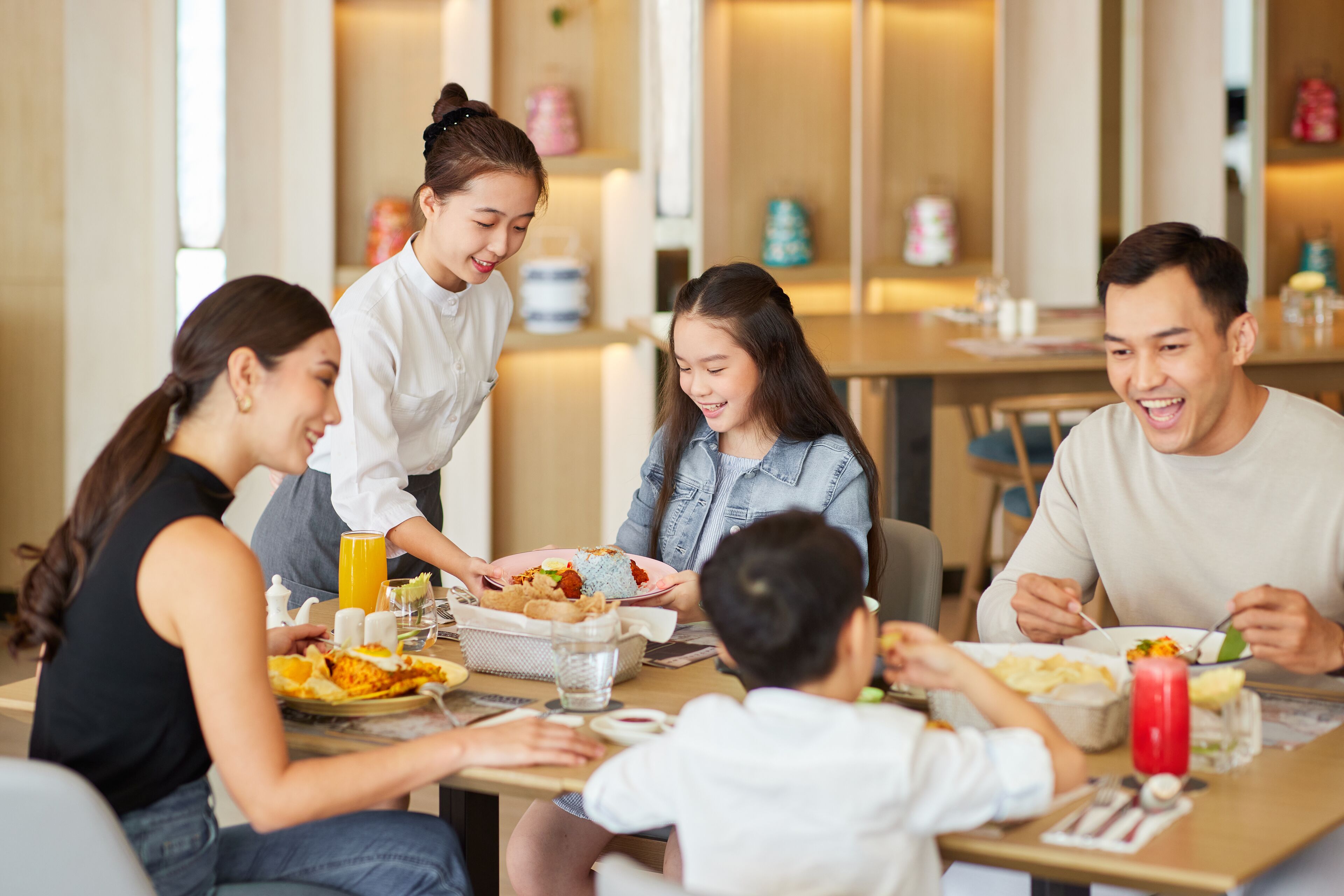 A group of people dining at a table with various dishes and drinks.