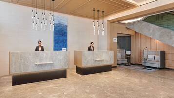 A reception area with marble counters, hanging pendant lights, and a staircase.