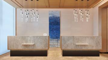 Een receptiezone met marmeren balies, hangende吊り下げ灯, en een blauwe structuurwand.