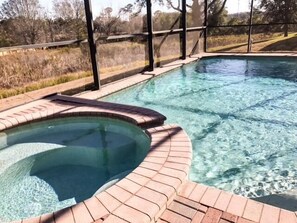 A clear swimming pool with a brick edge and a glass enclosure. - Extended Pool Deck With Spa 2 King Suites! 5 Bedroom Home by RedAwning (Davenport)