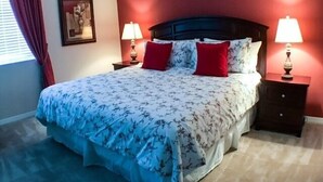 A neatly made bed with floral bedding, two bedside lamps, and a framed picture on the wall.