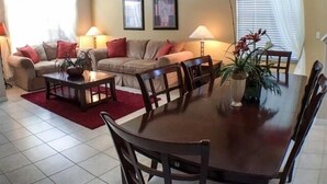 A living room with a sofa set, a dining table with chairs, and two lamps.