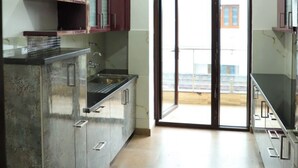 A kitchen with a central island, cabinets, and a sliding glass door leading to a balcony. - The Most Beautiful Property Of Rishikesh (Rishikesh)