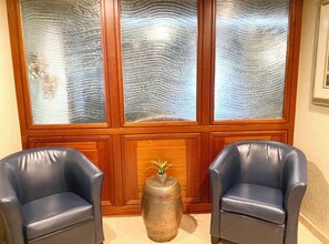 Relax in a traditional room with a classic ambiance, featuring a wooden paneled wall and large windows.