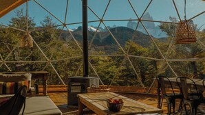 A geodesic dome with a wooden table, chairs, and a basket. - Chalten Camp - Glamping With A View (El Chalten)