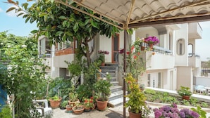 Un espacio al aire libre cubierto con plantas en macetas y una escalera que conduce a un edificio.