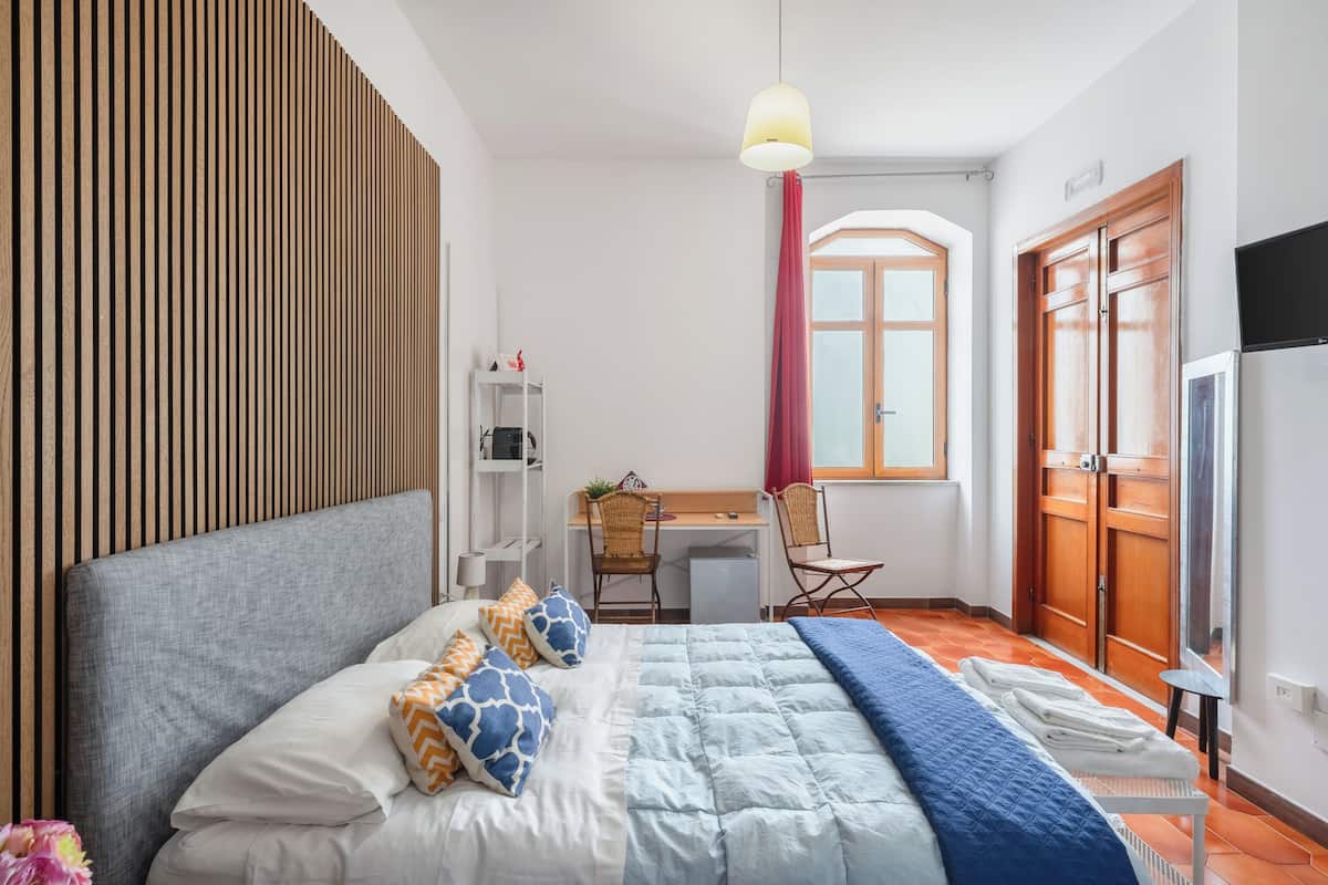 Ein Schlafzimmer mit Bett, Schreibtisch, Stuhl, Fernseher und Kleiderschrank.