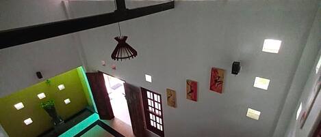 A staircase leading to a lower level with a green sofa and a small table, a window with blinds, and a wall with several framed pictures.