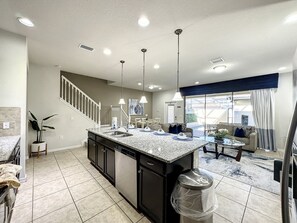 A modern kitchen with a central island, built-in appliances, and a dining area with a view. - Windsor-5 Bed W/splashpool-3801ww 5 Bedroom Townhouse by RedAwning (Kissimmee)