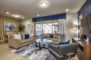 A spacious living room with a sofa set, a coffee table, and a dining area with chairs and a table. - Windsor-5 Bed W/splashpool-3801ww 5 Bedroom Townhouse by RedAwning (Kissimmee)