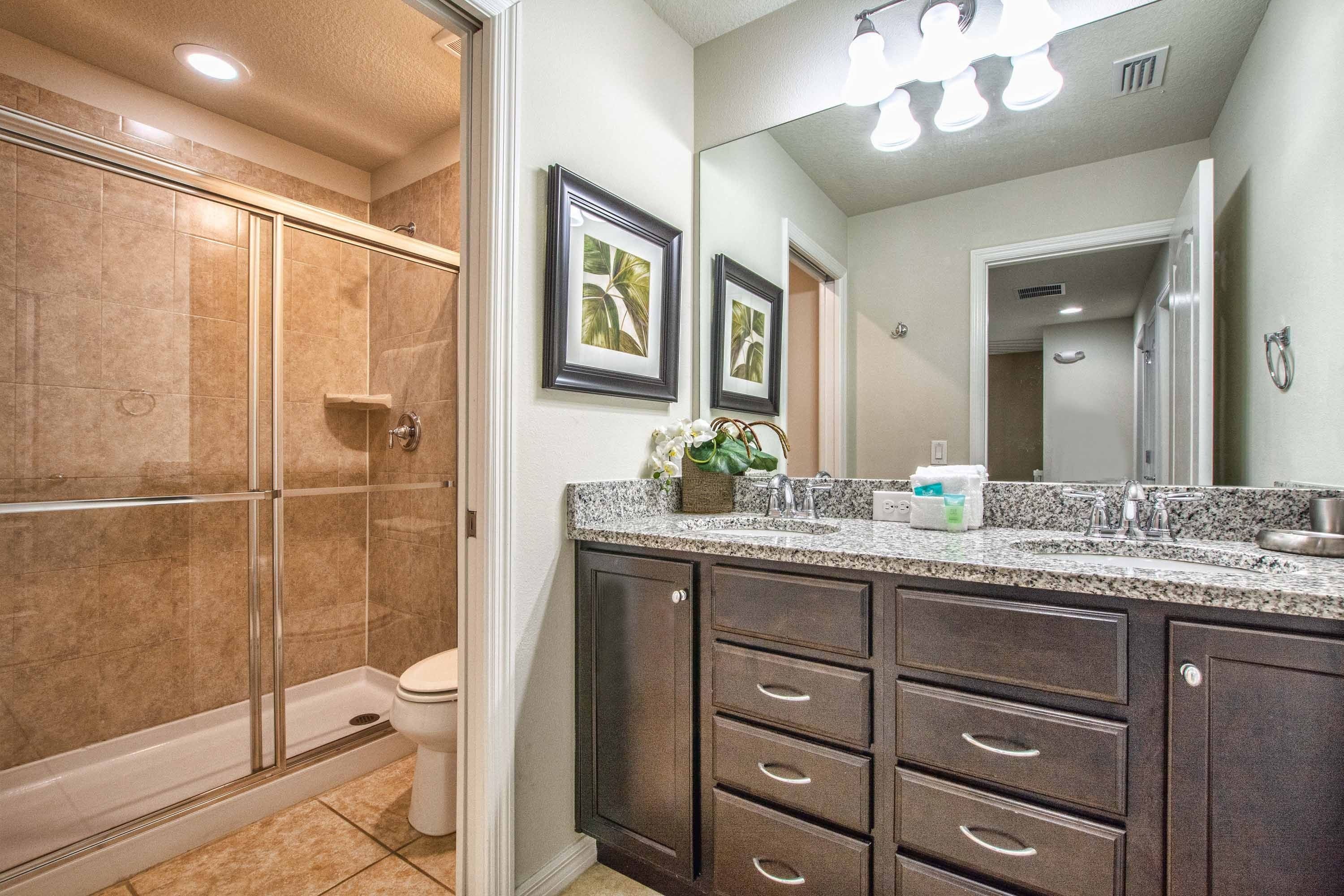 A modern bathroom with a walk-in shower, a large vanity with drawers, a mirror, and a sink.