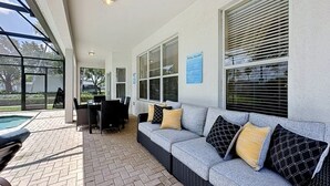 Un patio techado con piscina, mobiliario exterior y vistas del entorno.