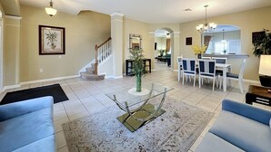 Un salón espacioso con escalera, comedor y cocina al fondo.