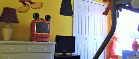 Habitación infantil con cama, cómoda y decoración de pared con temática de Mickey Mouse y Star Wars.