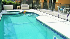 A swimming pool with a tiled edge, a lounge chair, and a small table. - Prime Location In Secure Safe 247 Manned Gatehouse Community With Clubhouse (Kissimmee)