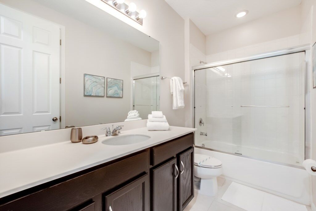 Une salle de bain moderne avec un meuble-lavabo à deux vasques, un grand miroir, une douche à parois de verre et des toilettes.