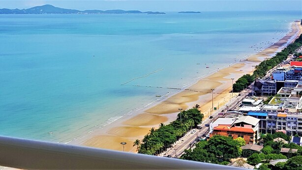 A coastal view with a beach, clear water, and buildings along the shore. - Beach Condo with Stunning Sea Views - Sleeps 2 (Pattaya)