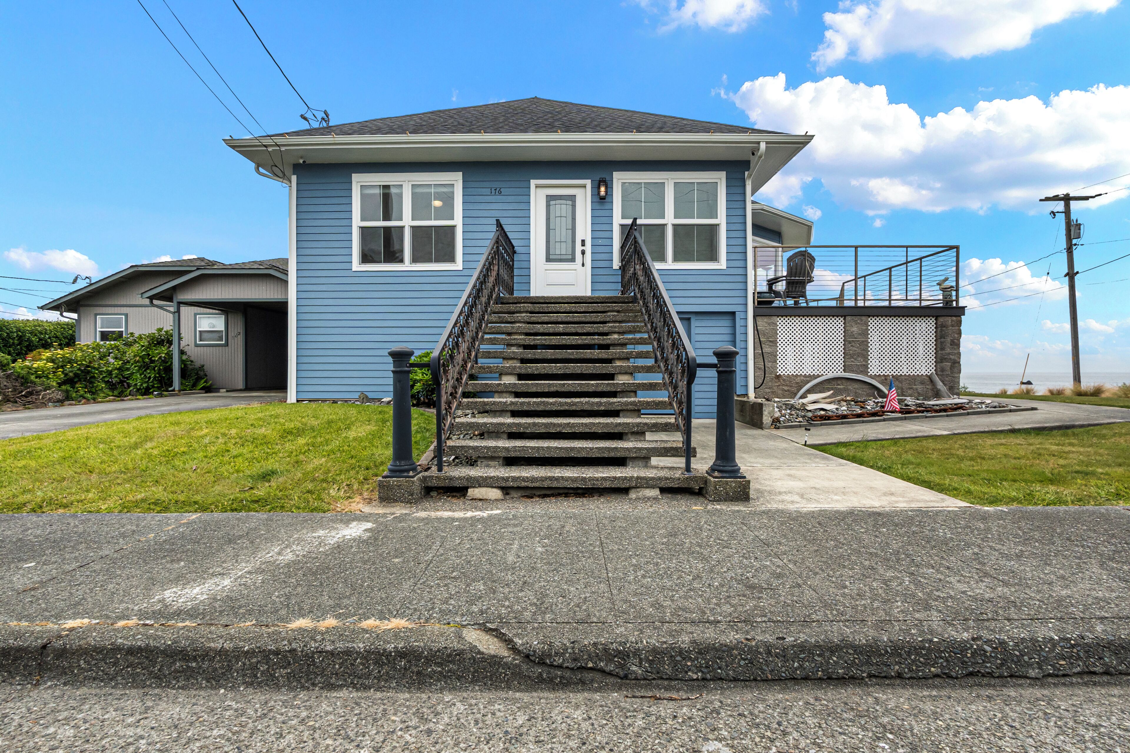 A two-story house with a front staircase, a garage, and a small porch with a railing.