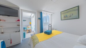 Ein Hotelzimmer mit Bett, Fernseher, Kleiderschrank und einem Bild an der Wand.