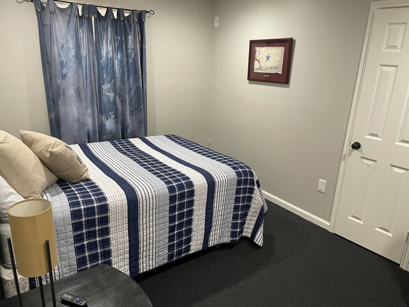 A bedroom with a bed, a lamp, a framed picture on the wall, and a door. - PRIVATE LAKE GETAWAY🎣 Swimming, Fishing & Relaxing at Charming Lakeside Bungalow (Conroe)
