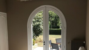 A bedroom with a large bed, a door leading to a patio, and a table with chairs outside.