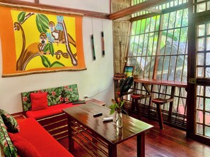 Une pièce avec une table en bois, un canapé rouge et un grand tableau représentant des singes dans un arbre.