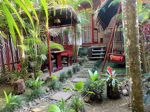 A tropical garden with a wooden bench, a swing, and a stone pathway.