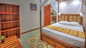 Una habitación con una cama, una estantería de madera y una mesita con una planta.