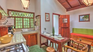 Una cocina compacta con estufa a gas, armarios de madera y un ventanal con vistas al verdor.