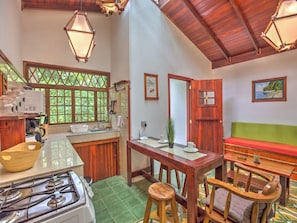 A compact kitchen with a gas stove, wooden cabinets, and a window with a view of greenery.