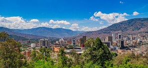 A cityscape with a mix of modern and traditional buildings, a mountainous backdrop, and a clear sky. - Apartamento En Envigado Super Comodo Y Lindo (Envigado)