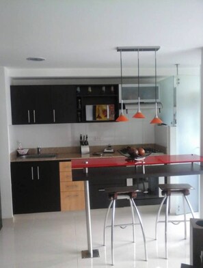 A modern kitchen with black cabinets, a red countertop, and two bar stools.