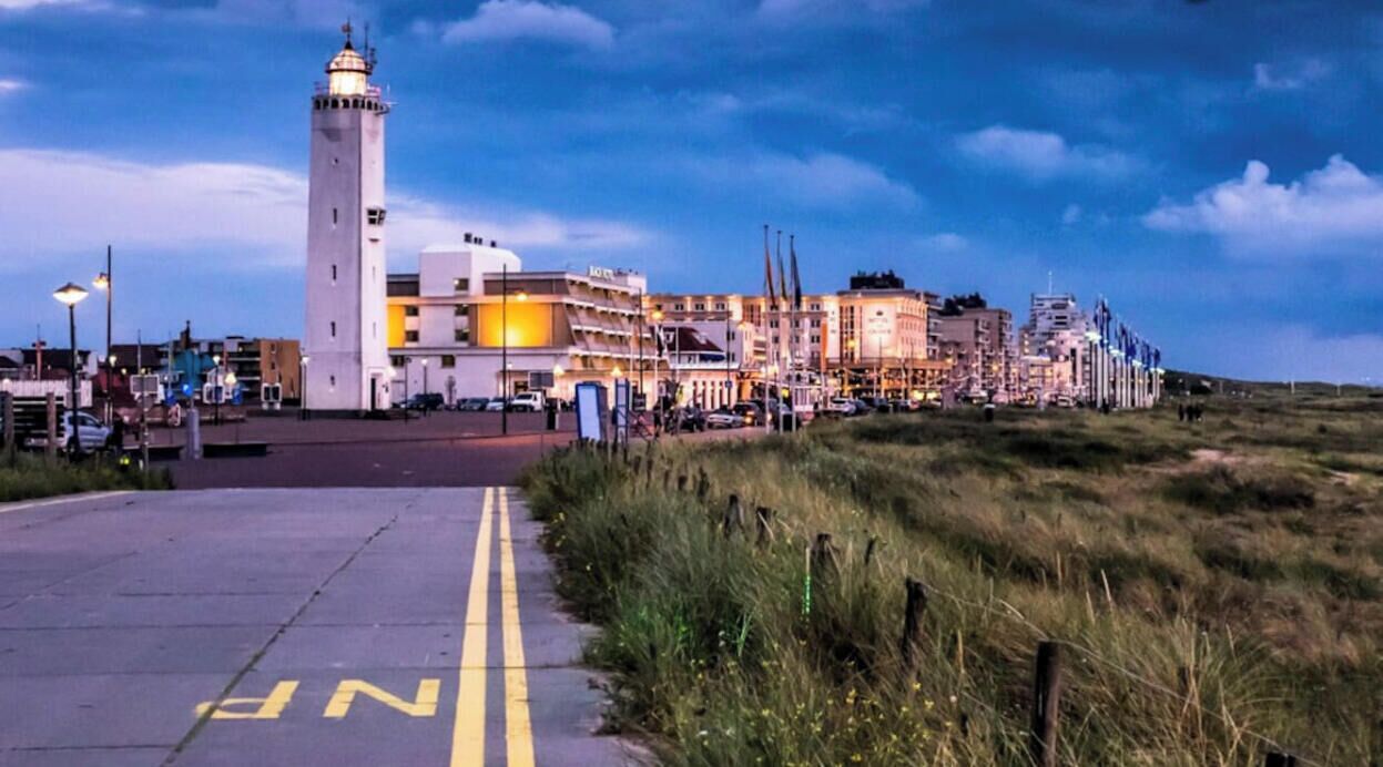 Een kustplaats met een opvallend vuurtoren, een modern hotel en een promenade.