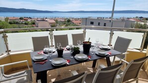 Une table à manger installée sur un balcon, avec vue sur un lac et des bâtiments en arrière-plan.