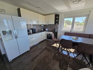 A modern kitchen with a built-in water dispenser, a microwave, a coffee maker, and a dining area with a table and chairs. - Villa Rocco in Split - Luxury - heated saltwater pool - up to 19 Guests (Kaštel Gomilica)