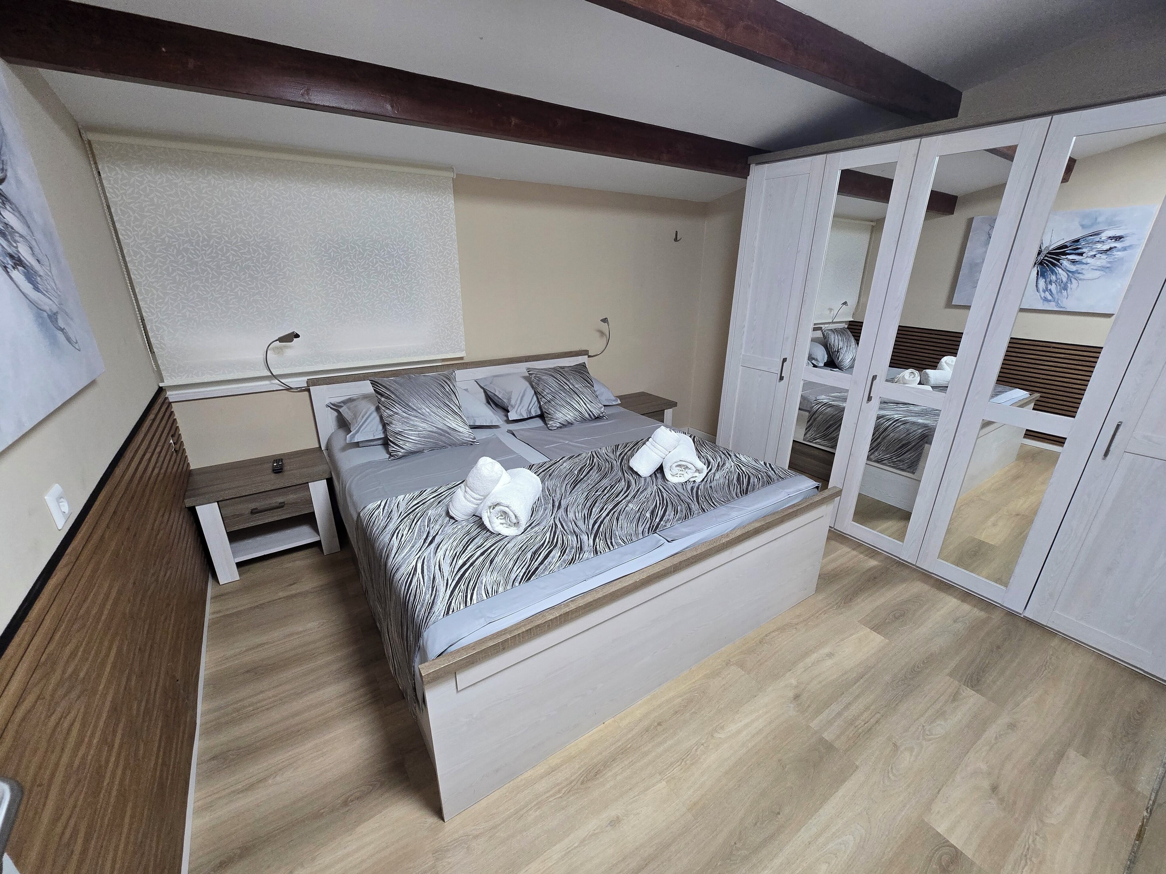 Ein Schlafzimmer mit Bett, Nachttischen, einem Kleiderschrank und einem Spiegel.