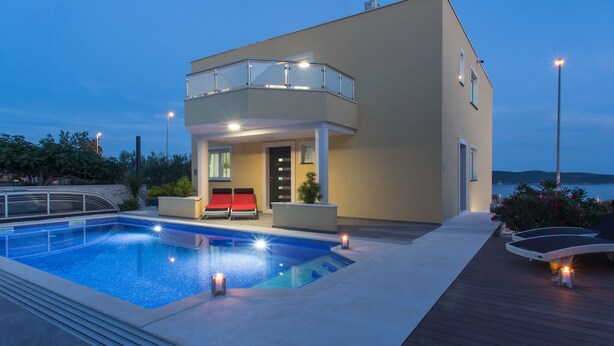 Un immeuble moderne doté d’une piscine, d’un balcon et offrant une vue sur l’eau.