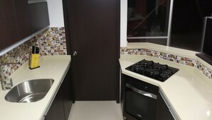 Uma cozinha com pia de aço inoxidável, fogão e lava-louças.